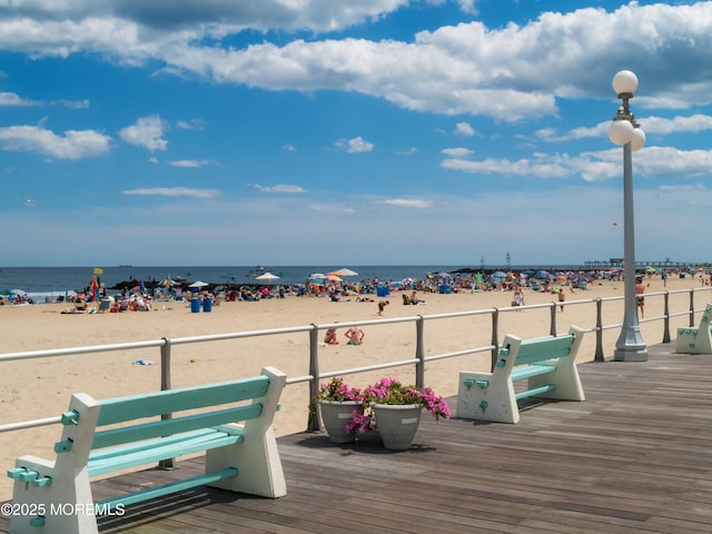 wooden terrace featuring a beach view and a water view