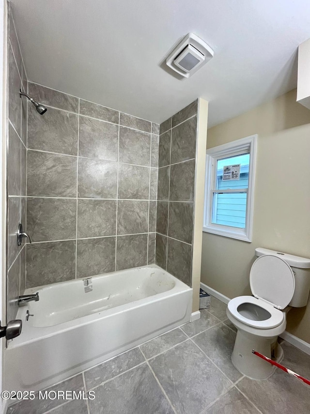 bathroom with tile patterned floors, tiled shower / bath combo, and toilet