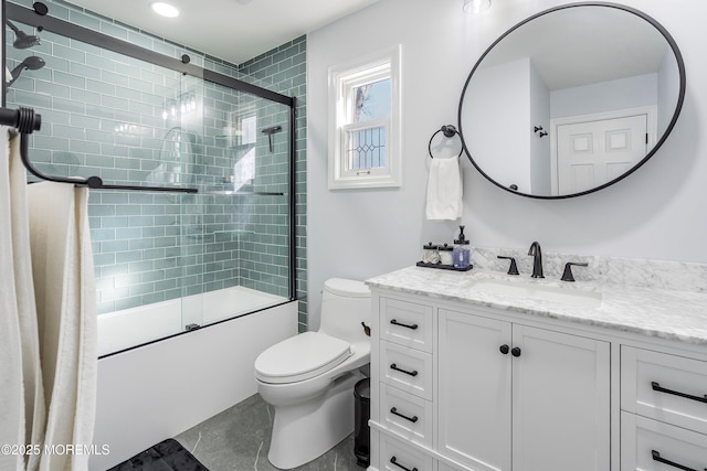 full bathroom featuring combined bath / shower with glass door, vanity, and toilet