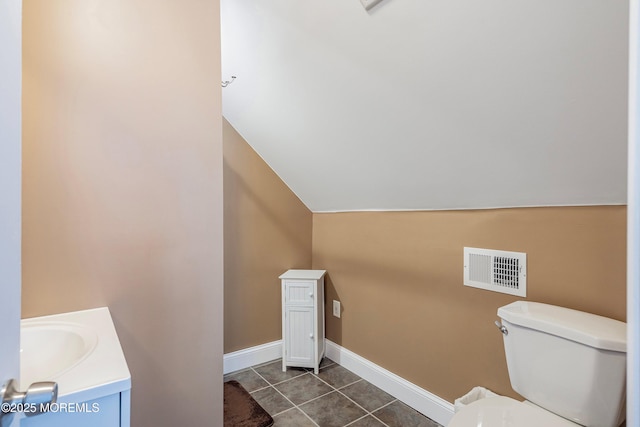 bathroom featuring tile patterned flooring, lofted ceiling, vanity, and toilet