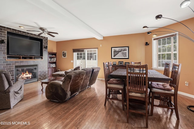 dining area with beamed ceiling, hardwood / wood-style flooring, a fireplace, and ceiling fan