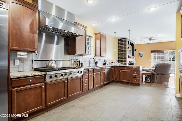 kitchen featuring ceiling fan, sink, stainless steel appliances, pendant lighting, and extractor fan