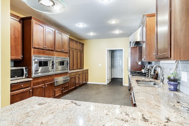 kitchen with stainless steel microwave, sink, tasteful backsplash, light stone counters, and light tile patterned floors