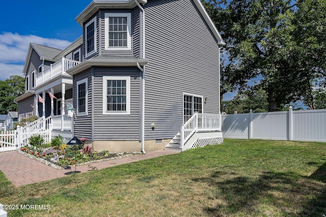 view of side of property featuring a balcony and a yard