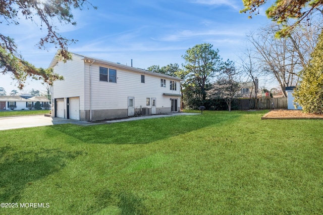 rear view of property featuring central air condition unit, a yard, and a garage