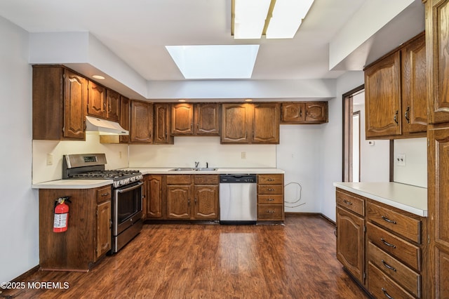 kitchen featuring dark wood-type flooring, a skylight, sink, and stainless steel appliances