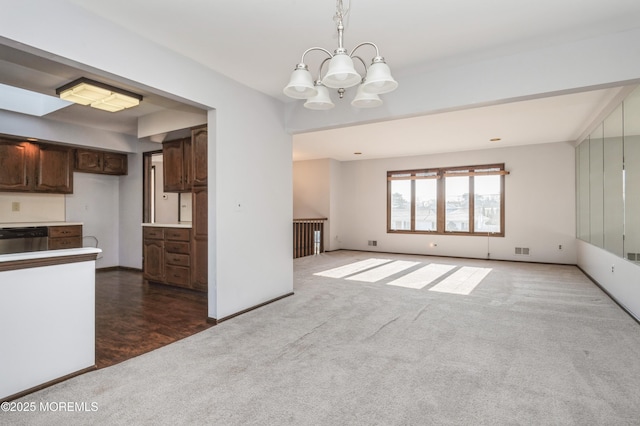 kitchen featuring an inviting chandelier, dark colored carpet, dark brown cabinets, pendant lighting, and stainless steel dishwasher