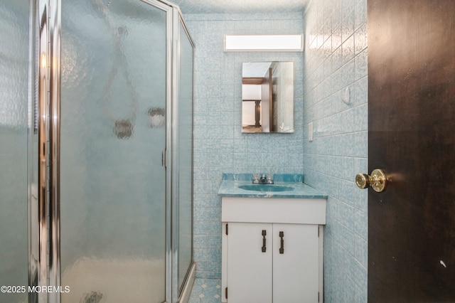 bathroom featuring a shower with shower door and vanity