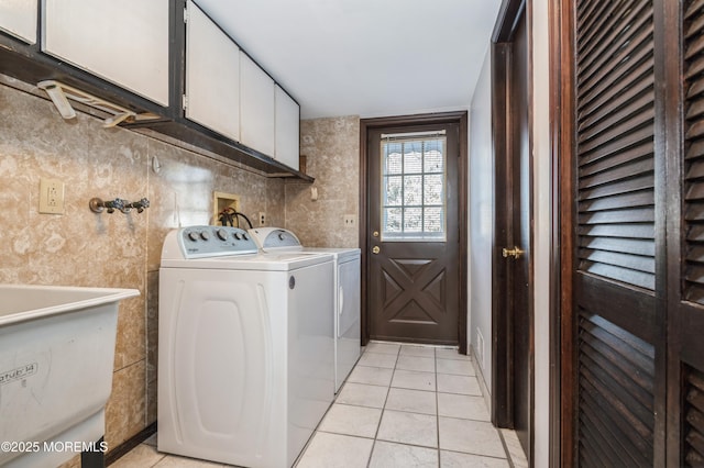 clothes washing area featuring cabinets, light tile patterned floors, independent washer and dryer, and sink