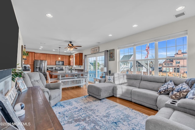 living room with ceiling fan and light hardwood / wood-style flooring