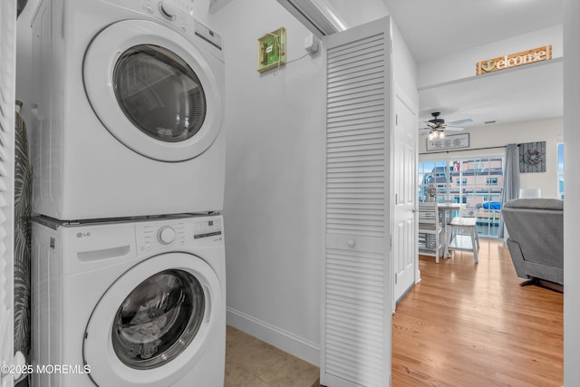 clothes washing area with ceiling fan, stacked washer and clothes dryer, and light wood-type flooring