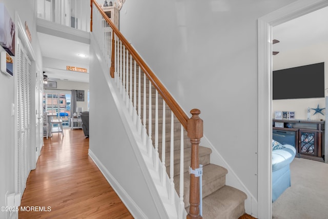 stairway with hardwood / wood-style floors and ceiling fan