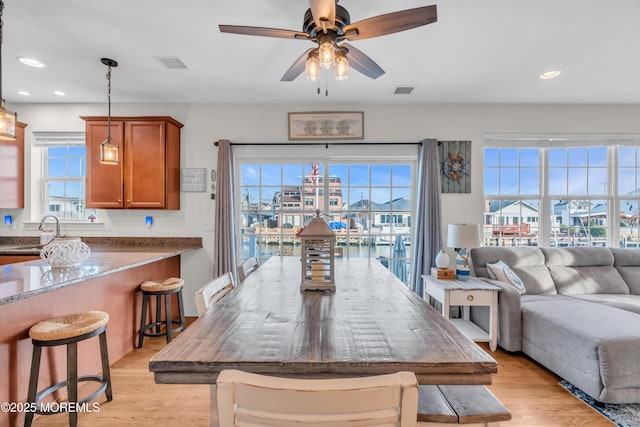 dining room with ceiling fan, light wood-type flooring, sink, and a wealth of natural light