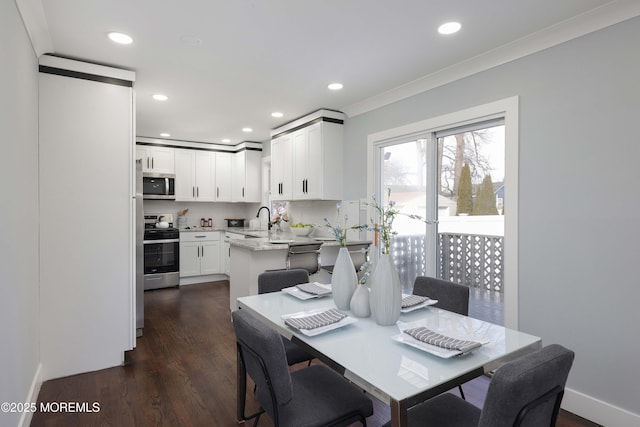 dining room with ornamental molding, dark hardwood / wood-style floors, and sink