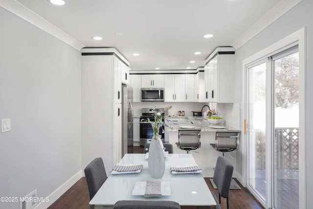 dining space featuring dark wood-type flooring, crown molding, and sink