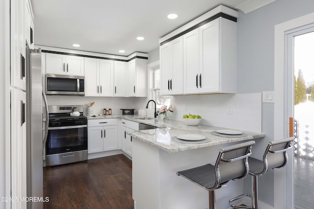 kitchen with kitchen peninsula, white cabinets, stainless steel appliances, and a breakfast bar area