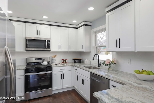 kitchen featuring sink, white cabinetry, stainless steel appliances, dark hardwood / wood-style flooring, and light stone counters