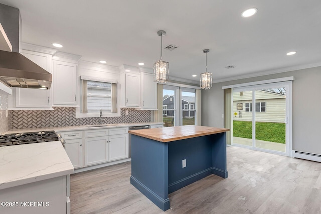 kitchen with a kitchen island, white cabinets, butcher block counters, and ventilation hood