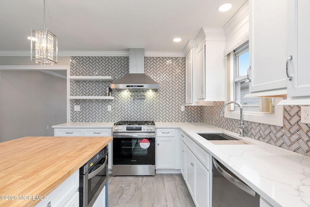 kitchen featuring white cabinetry, appliances with stainless steel finishes, wall chimney range hood, and sink