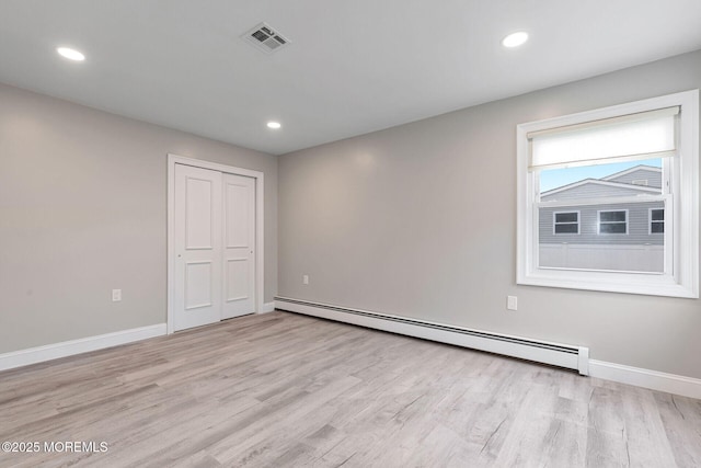 unfurnished room with a baseboard radiator and light hardwood / wood-style flooring