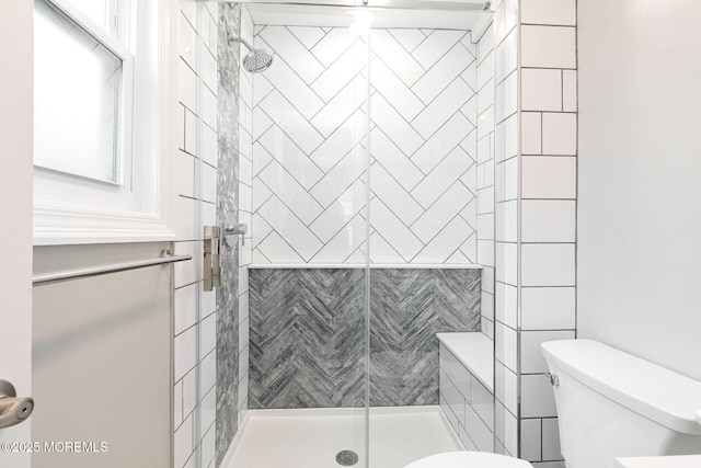 bathroom featuring toilet and a tile shower