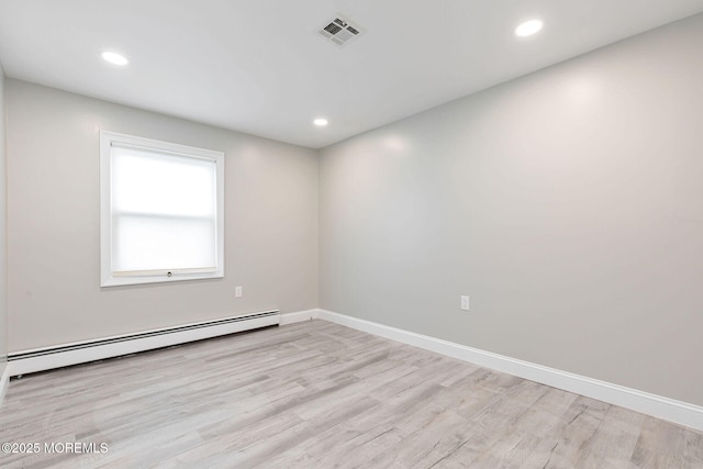 empty room with a baseboard heating unit and light hardwood / wood-style floors