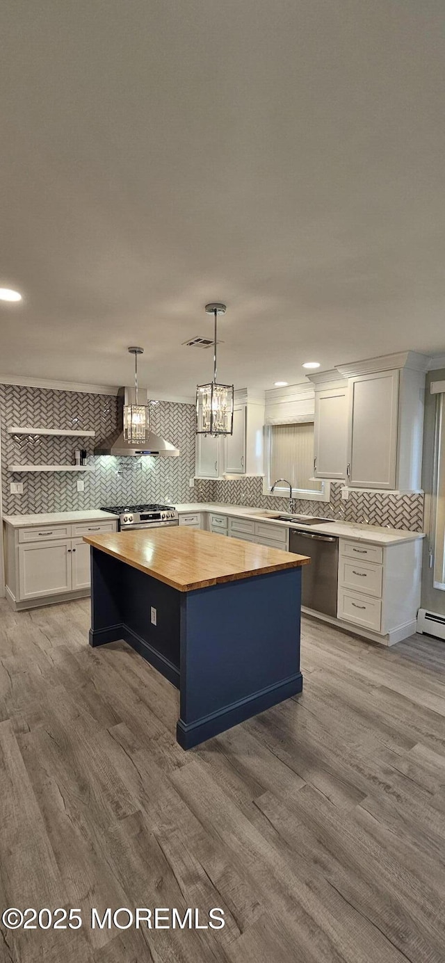 kitchen featuring pendant lighting, a center island, backsplash, white cabinetry, and appliances with stainless steel finishes