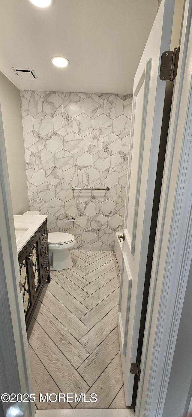 bathroom featuring tile walls, vanity, and toilet