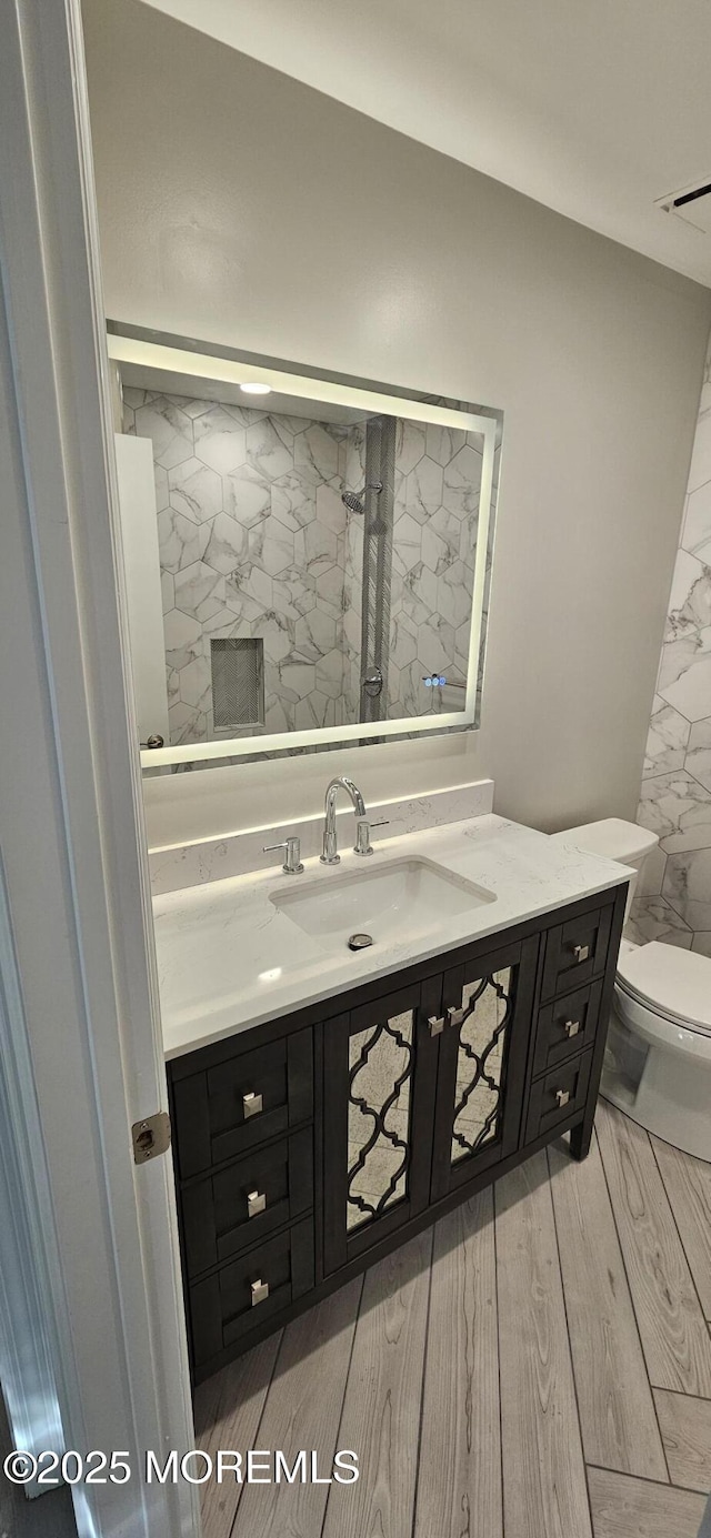 bathroom featuring toilet, vanity, and hardwood / wood-style flooring