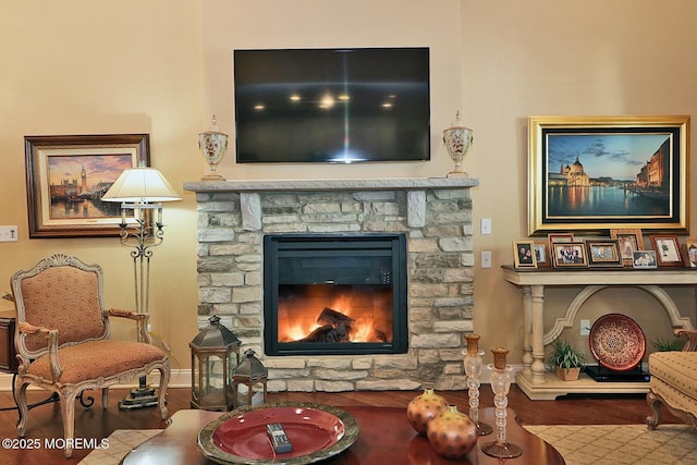 sitting room with a stone fireplace and hardwood / wood-style flooring