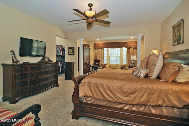 bedroom with a closet, carpet, ceiling fan, a walk in closet, and decorative columns