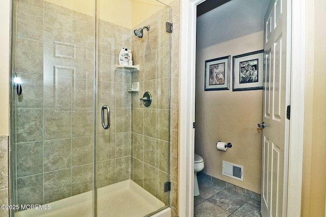 bathroom featuring a shower with door, tile patterned floors, and toilet