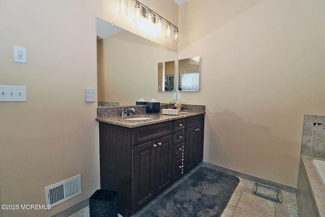 bathroom with tile patterned flooring, tiled bath, and vanity