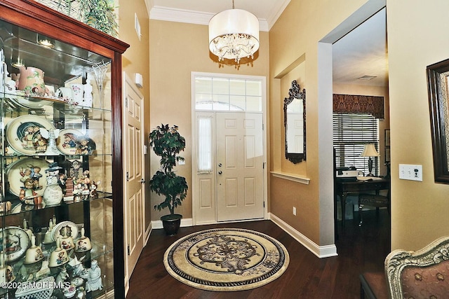 foyer entrance with dark wood-type flooring, crown molding, and a chandelier