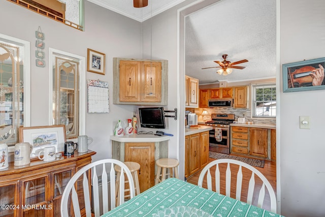 dining area with a textured ceiling, light hardwood / wood-style floors, ceiling fan, and ornamental molding