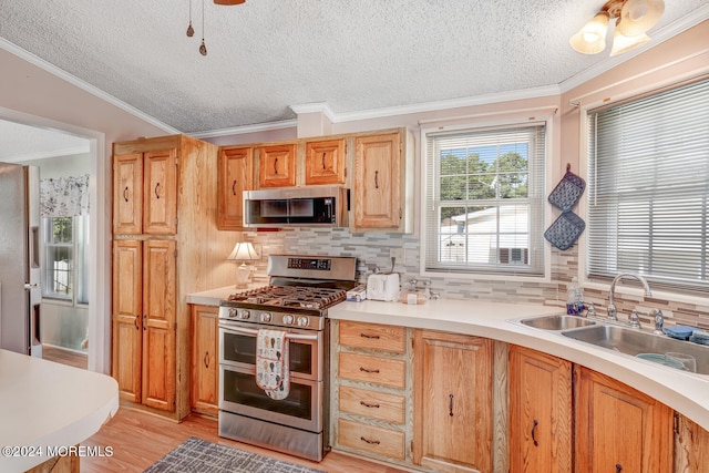 kitchen featuring tasteful backsplash, a textured ceiling, stainless steel appliances, sink, and light hardwood / wood-style flooring