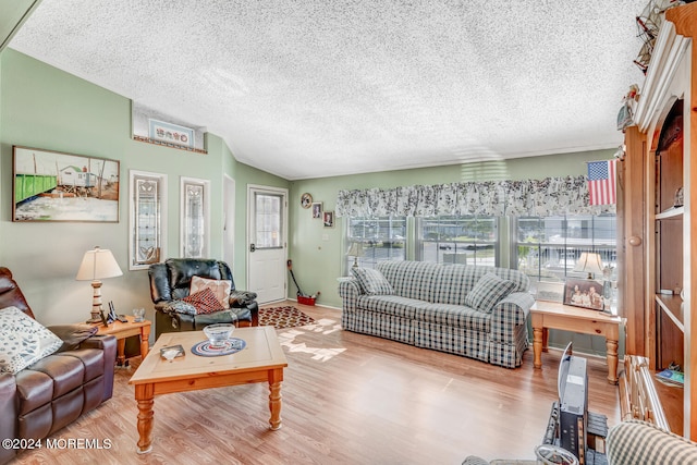 living room featuring light wood-type flooring, a textured ceiling, and lofted ceiling