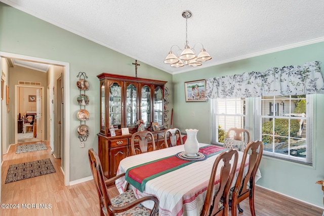 dining room featuring ornamental molding, a textured ceiling, an inviting chandelier, light hardwood / wood-style floors, and lofted ceiling