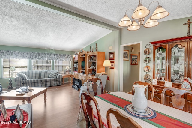 dining area featuring a chandelier, a textured ceiling, hardwood / wood-style flooring, and vaulted ceiling