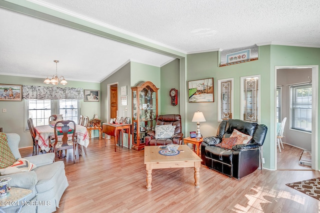 living room with a textured ceiling, light hardwood / wood-style floors, lofted ceiling, and a notable chandelier