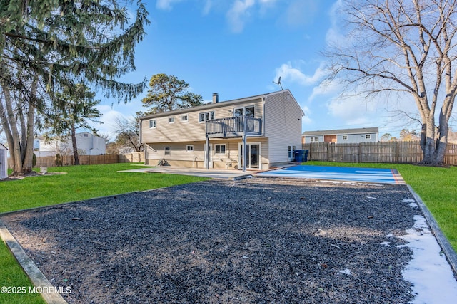 rear view of house with a patio area, a balcony, and a yard