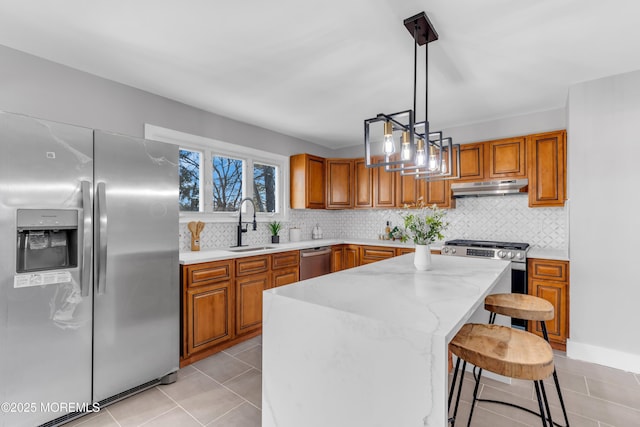 kitchen with stainless steel appliances, sink, decorative light fixtures, a center island, and a kitchen bar