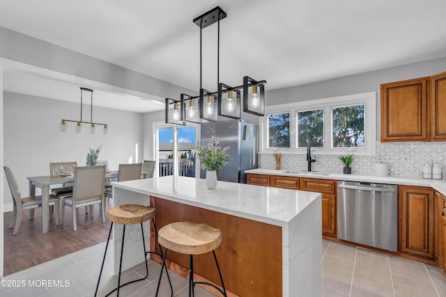 kitchen featuring a kitchen breakfast bar, hanging light fixtures, light stone countertops, a kitchen island, and appliances with stainless steel finishes