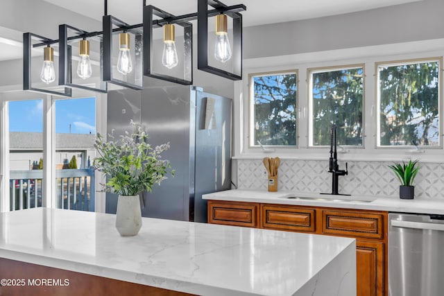 kitchen with appliances with stainless steel finishes, backsplash, pendant lighting, and sink