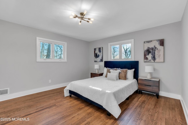 bedroom featuring an inviting chandelier and dark hardwood / wood-style floors