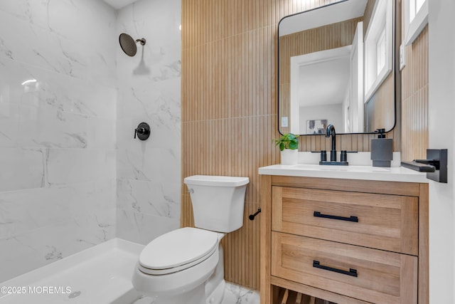 bathroom with toilet, a tile shower, and vanity