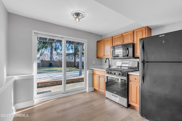 kitchen with sink, light wood-type flooring, and black appliances