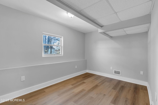 empty room with wood-type flooring and a paneled ceiling