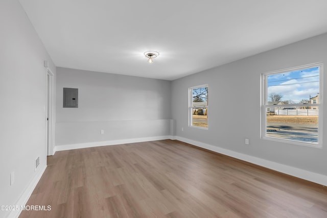 unfurnished room featuring light hardwood / wood-style floors, a wealth of natural light, and electric panel