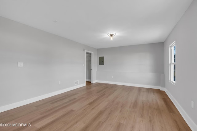 empty room featuring electric panel and light wood-type flooring